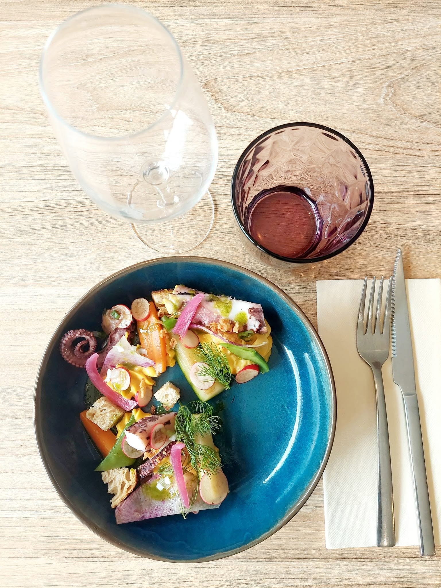 Assiette émaillée bleue d'un potier de Saint-Quentin-la-Poterie, garnie d'une entrée de saison